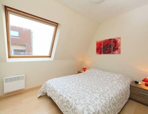 Une chambre à coucher comprenant un lit, une fenêtre, un radiateur et une œuvre d’art accrochée au mur.