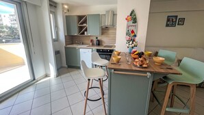 Una cocina moderna con comedor, que incluye una isla de cocina con taburetes, una mesa de comedor con sillas y vistas al exterior.