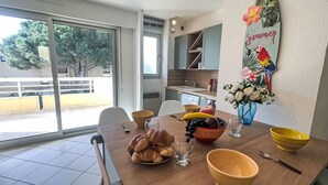Una mesa de comedor con comida y bebidas, una zona de cocina con armarios y vistas al exterior.