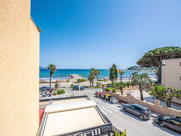 Vue d’une rue côtière avec un restaurant appelé « Grill » et une vue sur la plage et la mer.