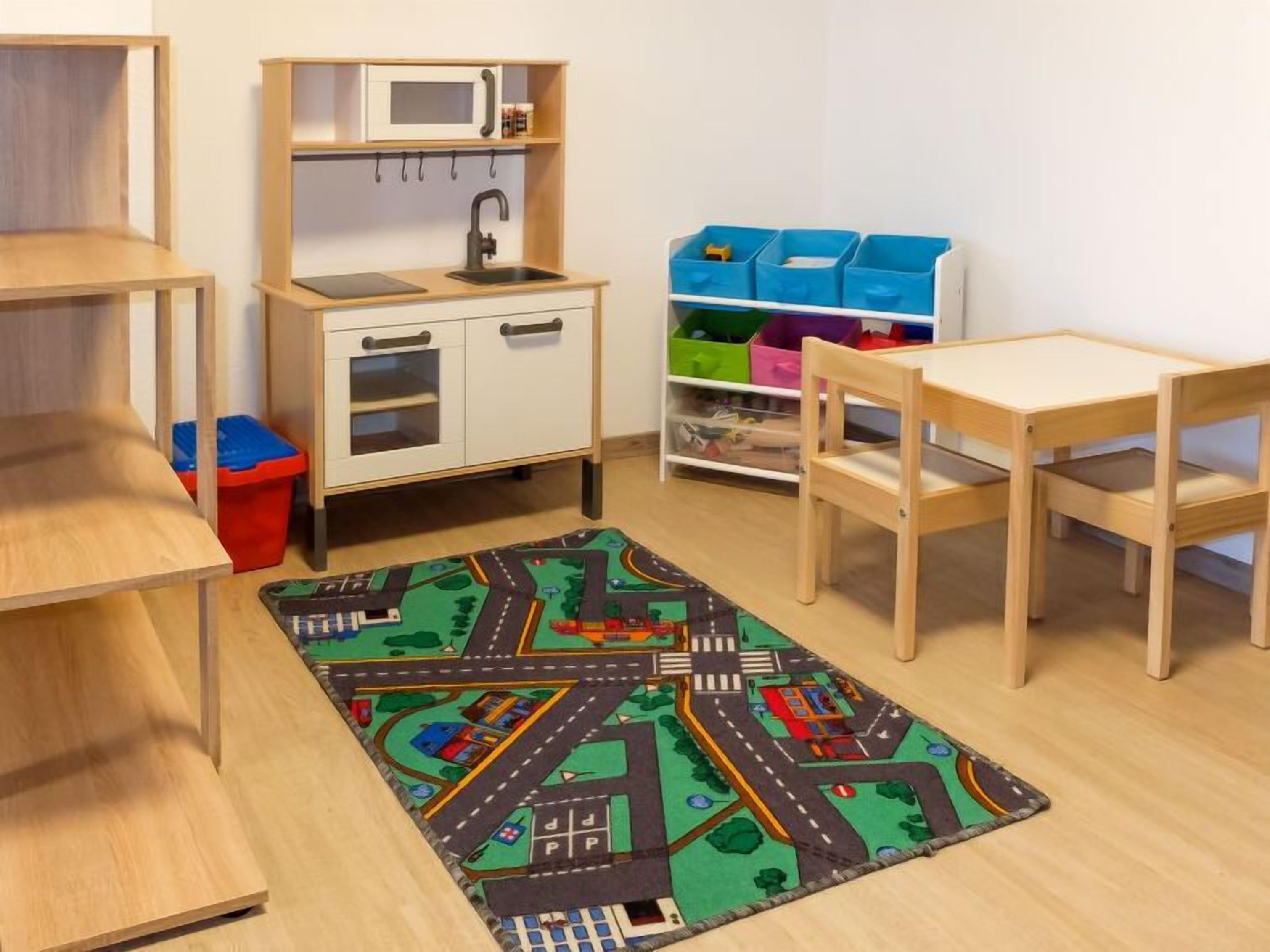 A child's playroom with a wooden desk, chair, and storage units.
