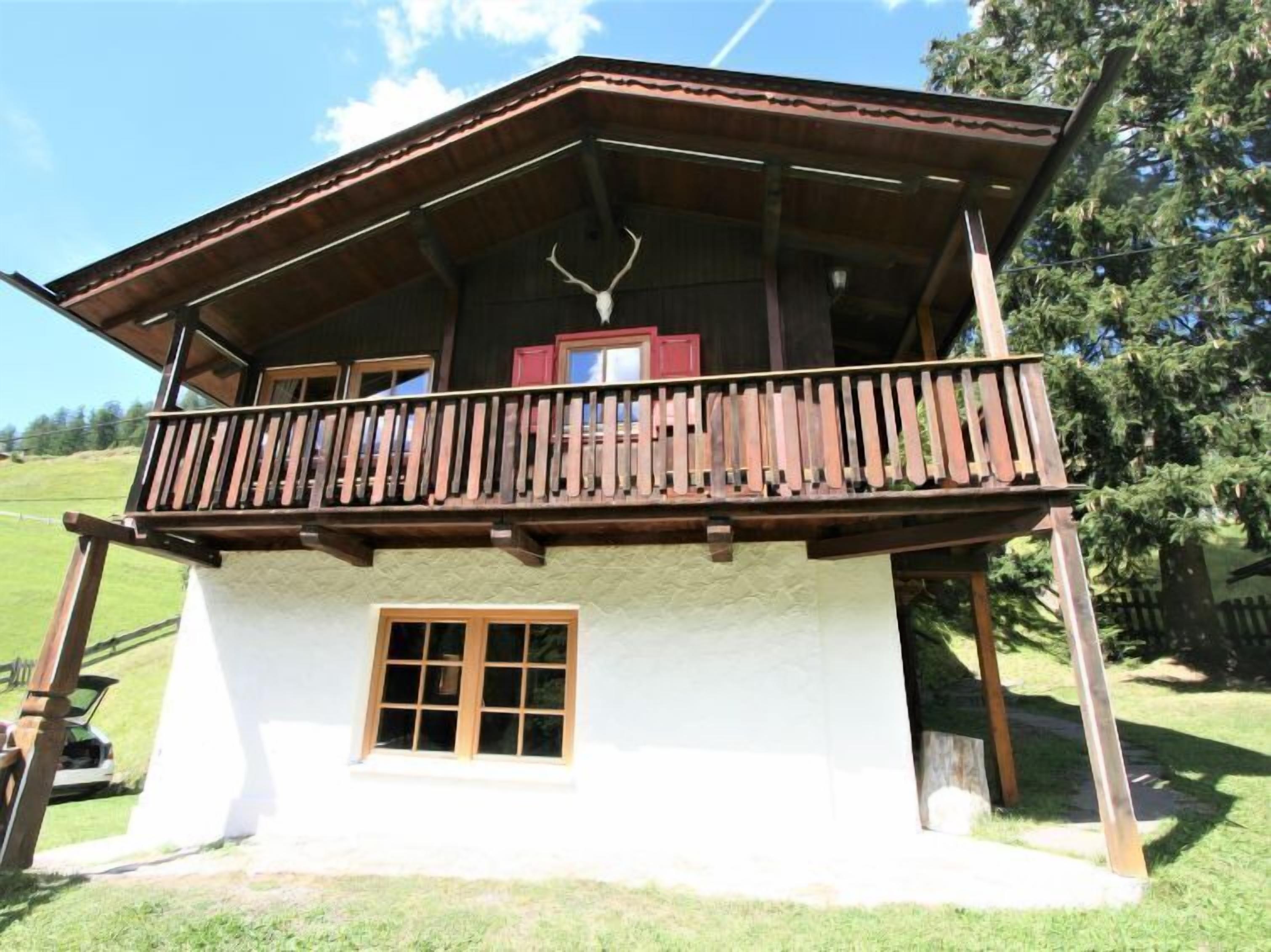 Ein Chalet mit Balkon, einer Holztür und einem Fenster.