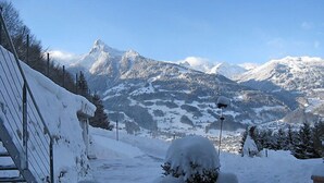Ein verschneiter Bergpfad mit einer Holzbank und einer Laterne.