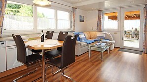 Ein modernes Wohnzimmer mit Essbereich, großen Fenstern und Blick ins Freie.