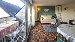 A cozy room with a checkered floor, a sofa with green cushions, a table with a striped tablecloth, and a chair. - Les Embruns by Interhome (Carnac)