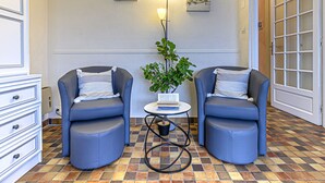 A room with two blue armchairs, a small round table with a book and a potted plant, and a wall-mounted lamp. - Les Embruns by Interhome (Carnac)