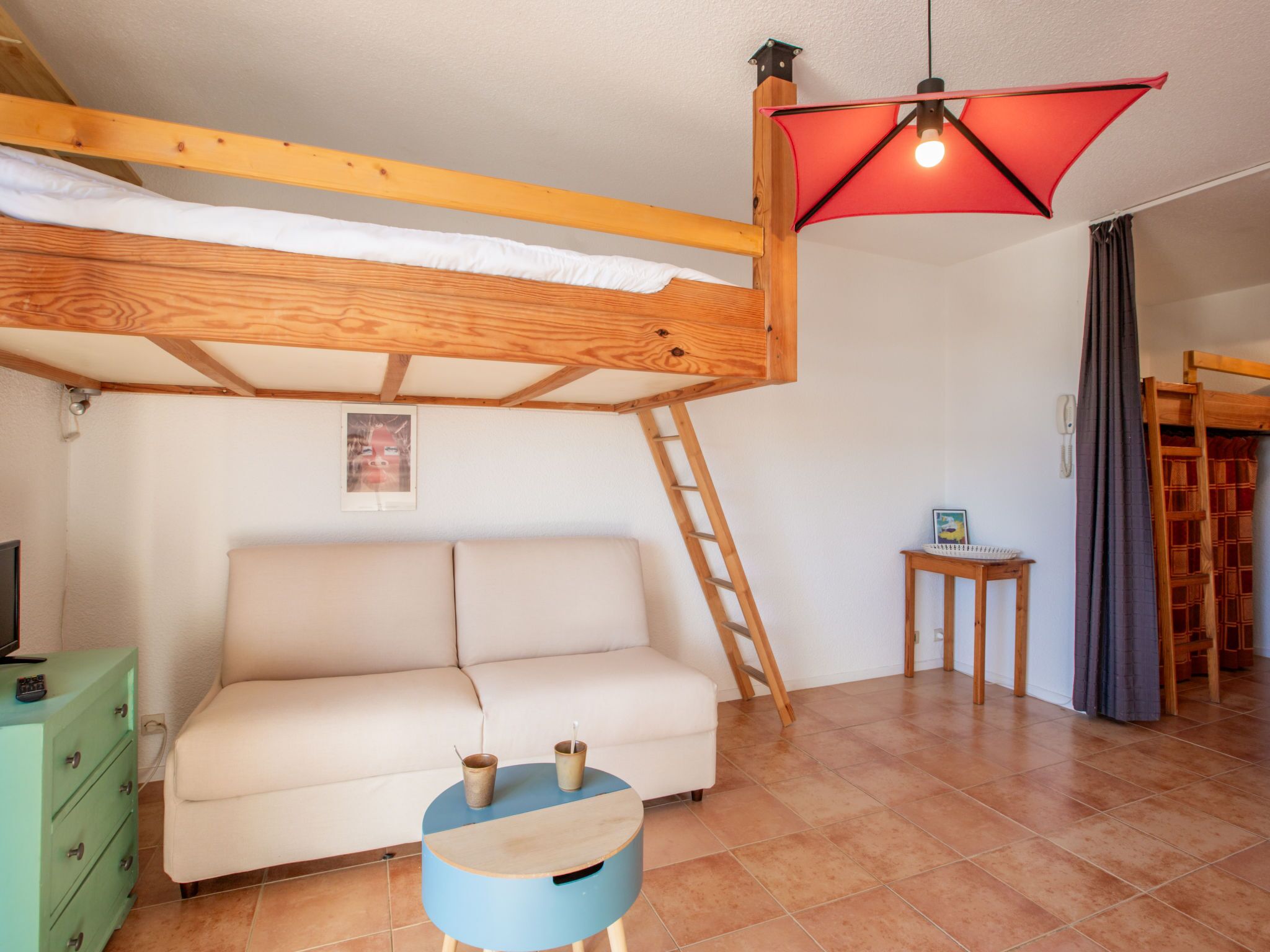Une pièce chaleureuse avec un lit superposé, une petite table ronde, un canapé et une échelle.