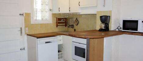 A compact kitchen with white cabinets, a microwave, a coffee maker, and a dishwasher.