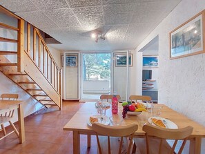 Un espace repas comprenant une table en bois, des chaises et un escalier.