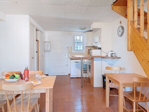 A compact kitchen with a dining area, a wooden staircase, and a clock on the wall. - Super Ile Rousse by Interhome (Bandol)