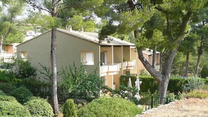 Un bâtiment à deux étages doté d’un balcon, entouré de verdure et d’arbres.