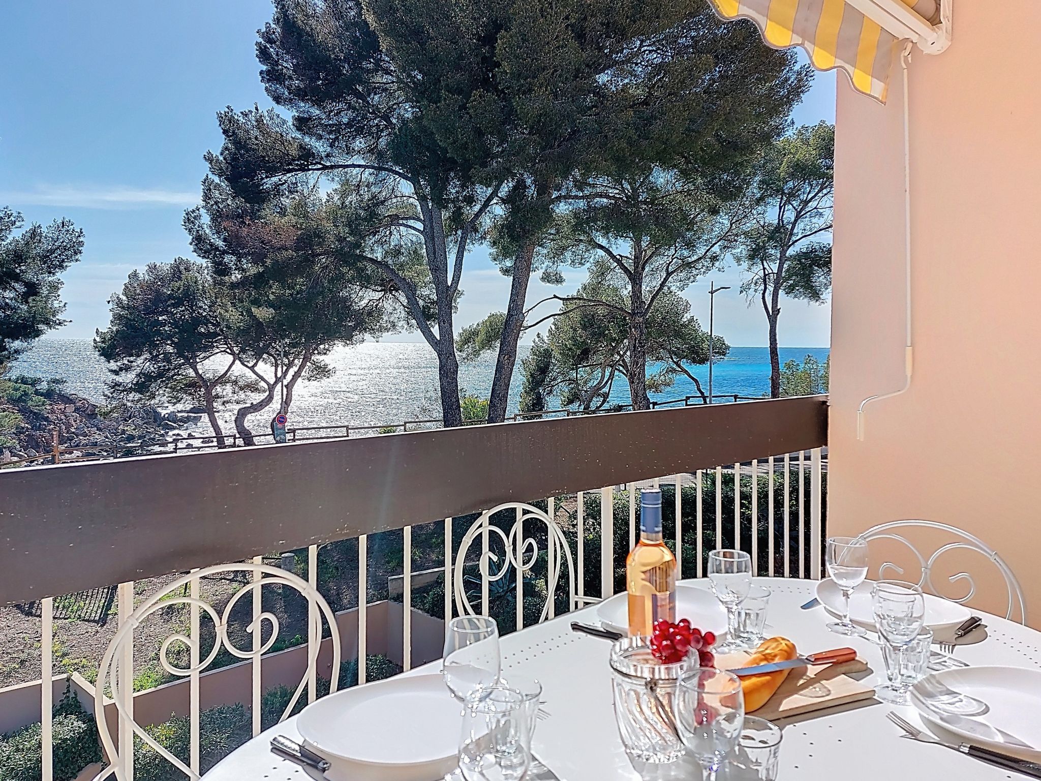 A table set for dining with a view of the sea and trees.