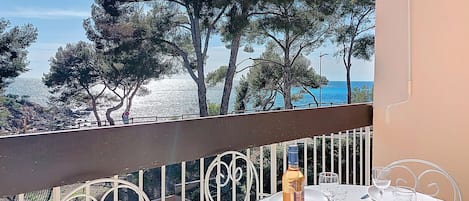 A table set for dining with a view of the sea and trees.
