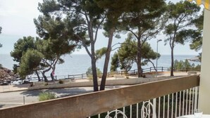 Un balcon avec vue sur la mer, une table dressée avec de la vaisselle et une rambarde.