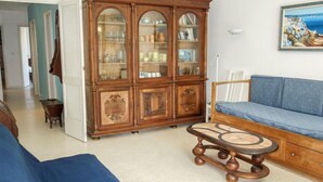Un salon avec un meuble en bois, un canapé bleu et une petite table ronde.