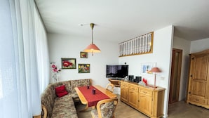 A cozy living room with a sofa, dining table, and wooden cabinets.