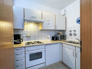 Een koelkast, een magnetron, een oven, kookgerei, borden en bestek