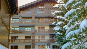 A multi-story building with balconies, labeled "VITALIS," surrounded by snow-covered trees. - Vitalis by Interhome (Zermatt)