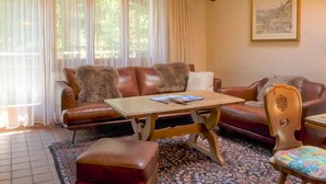A cozy living room with a brown leather sofa, a wooden coffee table, and a patterned rug. - Vitalis by Interhome (Zermatt)