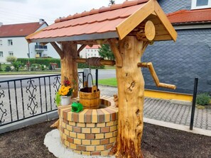 A wooden structure with a brick base, a metal roof, and a wooden bucket. - Schneider by Interhome (Geschwenda)