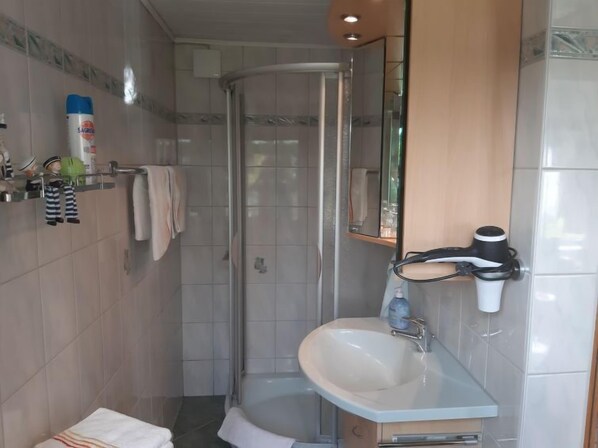 A compact bathroom with a glass shower enclosure, a sink with a mirror, and a towel rack. - Schneider by Interhome (Geschwenda)