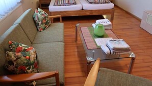 A cozy room with a bed, a sofa, a chair, and a small table with a green vase and a folded towel. - Vacation home Roth by Interhome (Ichenheim)