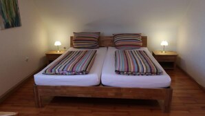 A double bed with striped bedding, two bedside tables with lamps, and a wooden floor. - Vacation home Roth by Interhome (Ichenheim)