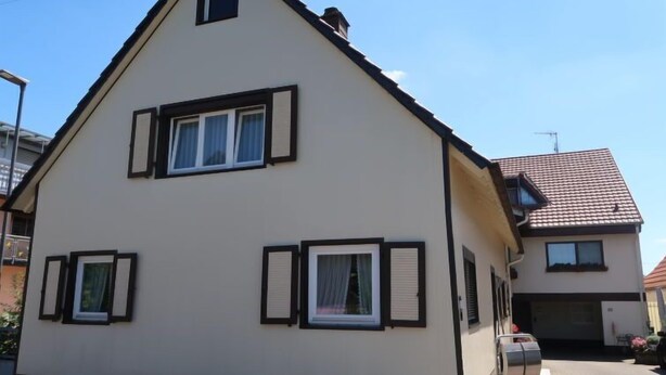 A two-story house with a gabled roof, multiple windows with shutters, and a visible garage door. - Vacation home Roth by Interhome (Ichenheim)