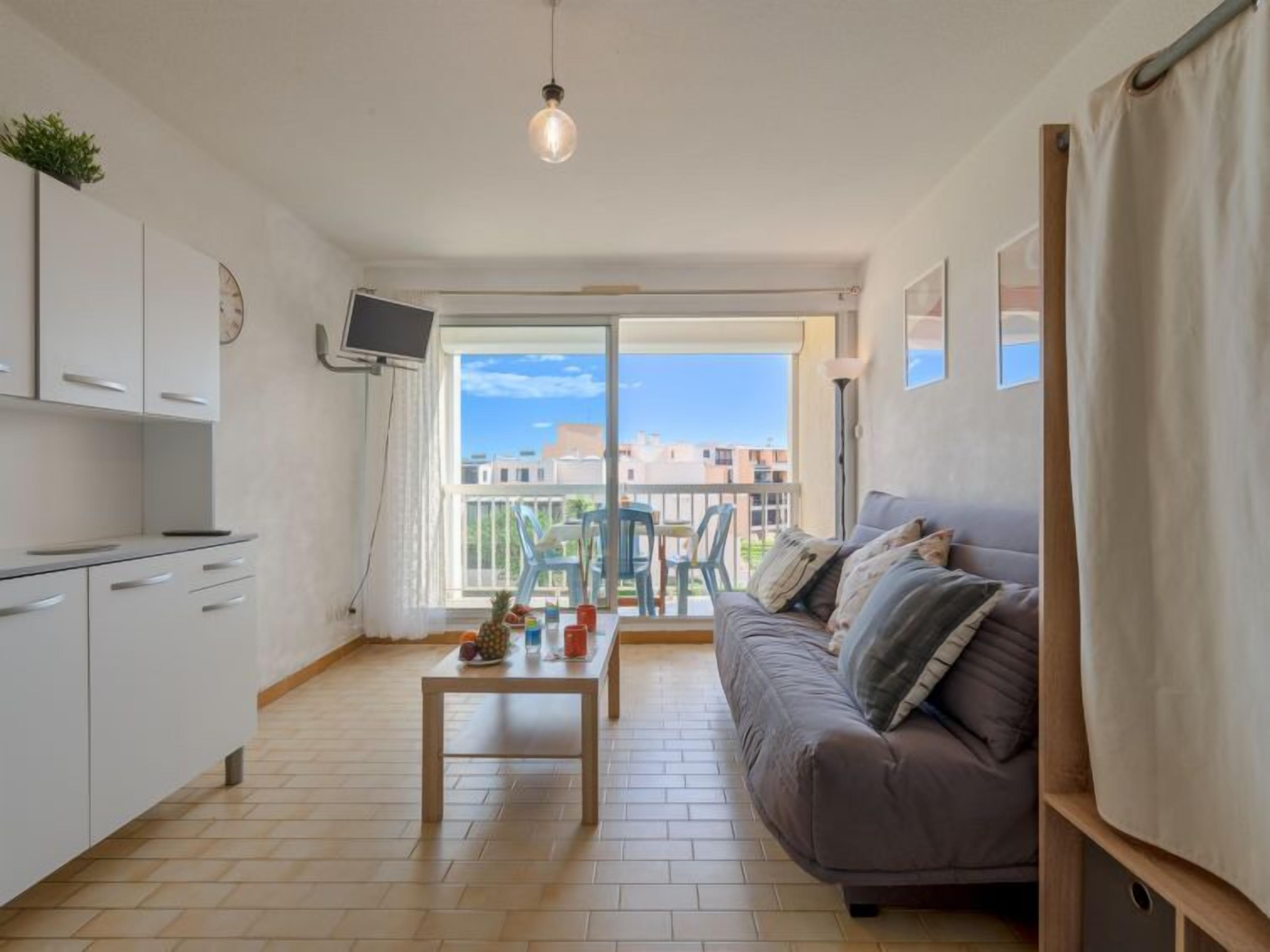 Ein modernes Apartment mit Balkon, einer Couch, einem Couchtisch und einem Fernseher.