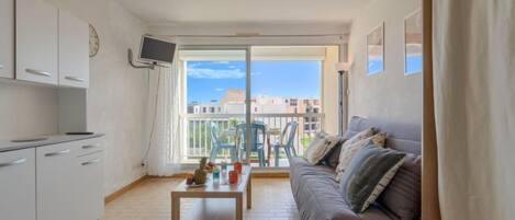 Ein modernes Apartment mit Balkon, einer Couch, einem Couchtisch und einem Fernseher.