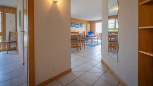 A spacious living area with a dining table and chairs, a wooden floor, and a large mirror on the wall. - Seya 19 by Interhome (Ovronnaz)