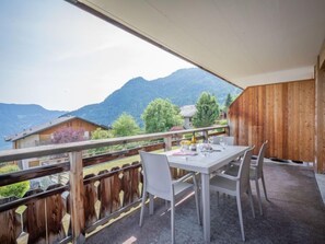 Ein Balkon mit Tisch und Stühlen mit Blick auf eine gebirgige Landschaft.