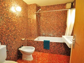 A bathroom with a mosaic tile wall, a bathtub, a shower, a toilet, and a sink. - Apartment Lani by Interhome (Zermatt)