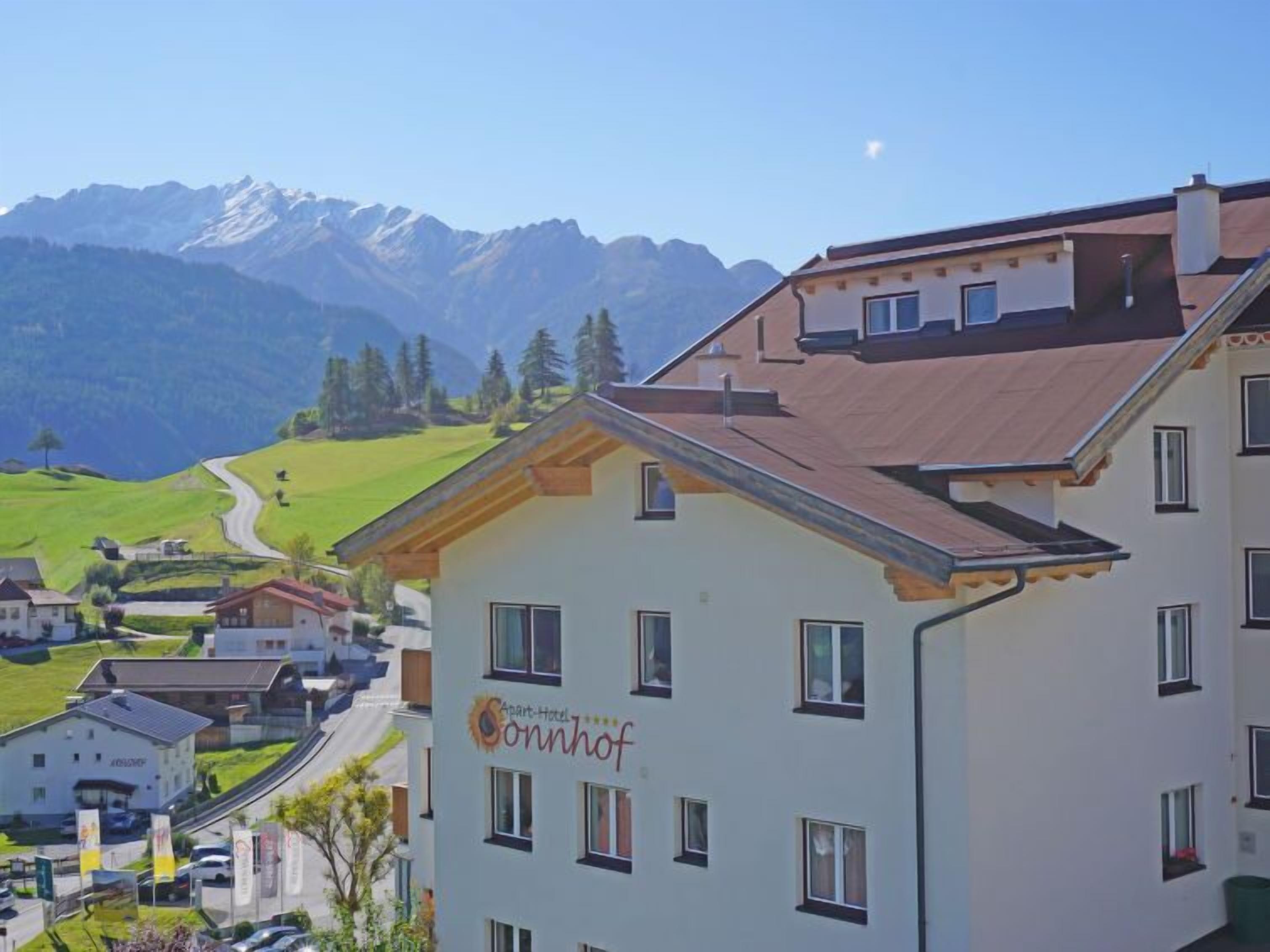 A hotel with a sign reading "Sonnhof" in a mountainous area with a road and other buildings in the foreground.
