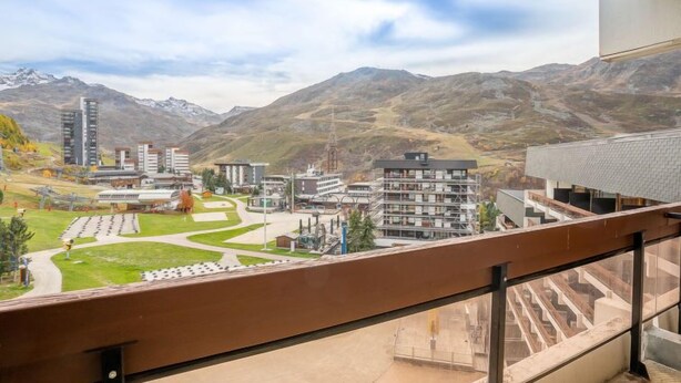 Un balcón con vistas a un paisaje montañoso, edificios y cielo despejado.