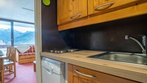 Una cocina con armarios de madera, un lavamanos de acero inoxidable y un lavavajillas.