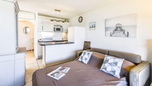 Un dormitorio moderno con sofá cama, una kitchenette pequeña y un comedor.