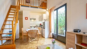 A modern kitchen with a dining area, wooden staircase, and a view through a large window. - Les Maisons de la Plage by Interhome (Le Grau du Roi)