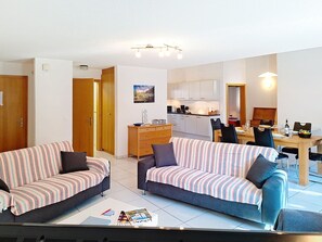 Un apartamento moderno con dos sofás a rayas, una mesa de comedor y una zona de cocina.
