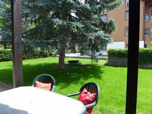 Ein Innenhof mit Tisch und Stühlen, ein großer Baum und ein Gebäude im Hintergrund.