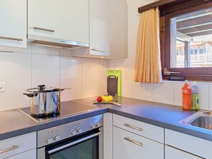 Una cocina moderna con estufa, horno y una ventana con cortinas.