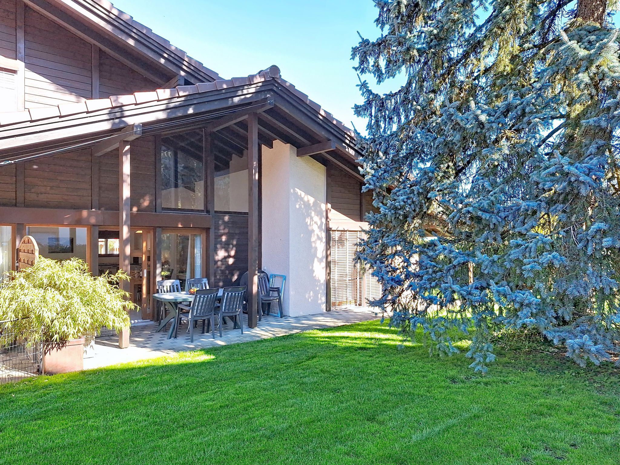A modern building with a covered patio area, outdoor seating, and a well-maintained lawn.