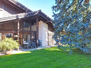 Ein modernes Gebäude mit überdachter Terrasse, Sitzgelegenheiten im Freien und einem gepflegten Rasen.