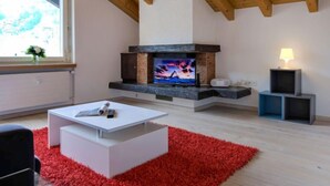 Un salon moderne avec une cheminée, une table basse blanche, un tapis rouge et une fenêtre donnant sur un beau paysage.