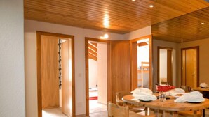 Un coin repas en bois, avec une table ronde et des chaises, des portes en bois et un plafond avec des poutres en bois.