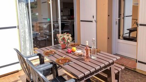 En terrasse med et bord dækket til to personer, en stol og en potteplante.