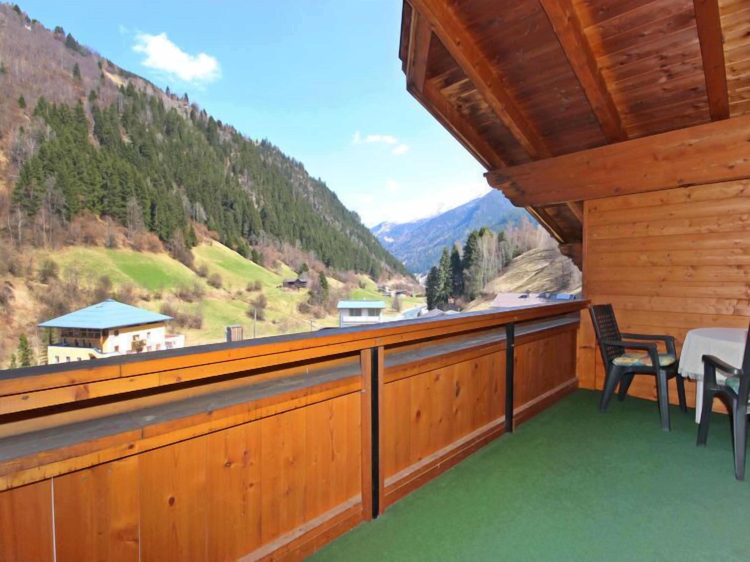 Ein Holzbalkon mit Blick auf ein Tal und Berge.