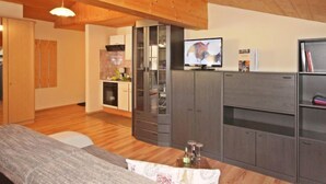 A modern living room with a wooden ceiling, a sofa, a TV, and built-in cabinets. - Voräule by Interhome (See)