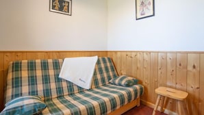 Un banc en bois avec un coussin à carreaux, un petit tabouret en bois et deux tableaux encadrés accrochés au mur.