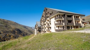 Un hôtel à plusieurs étages, doté d’une architecture moderne, situé dans une région vallonnée sous un ciel d’un bleu éclatant.
